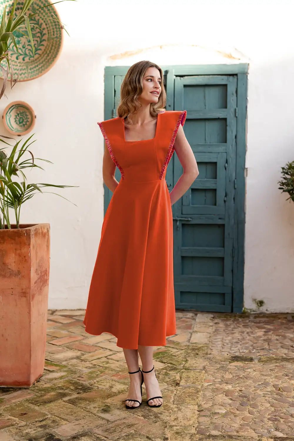 Vestido midi naranja con flecos en los hombros.