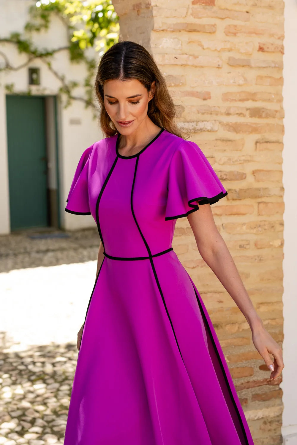 Vestido midi fucsia con vivos de decoración y volantes en las mangas.