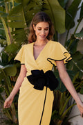 Vestido midi amarillo con flor negra en la cintura. Cuello en forma de pico.