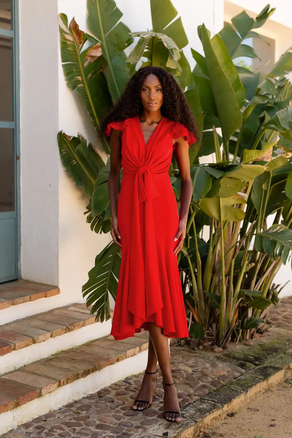 Vestido midi rojo con volantes y lazo en la cintura.