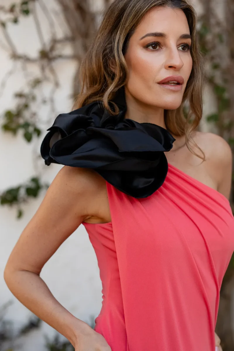 Vestido midi coral de punto con una flor en el hombro de tafeta. Espalda y escote asimétrico.