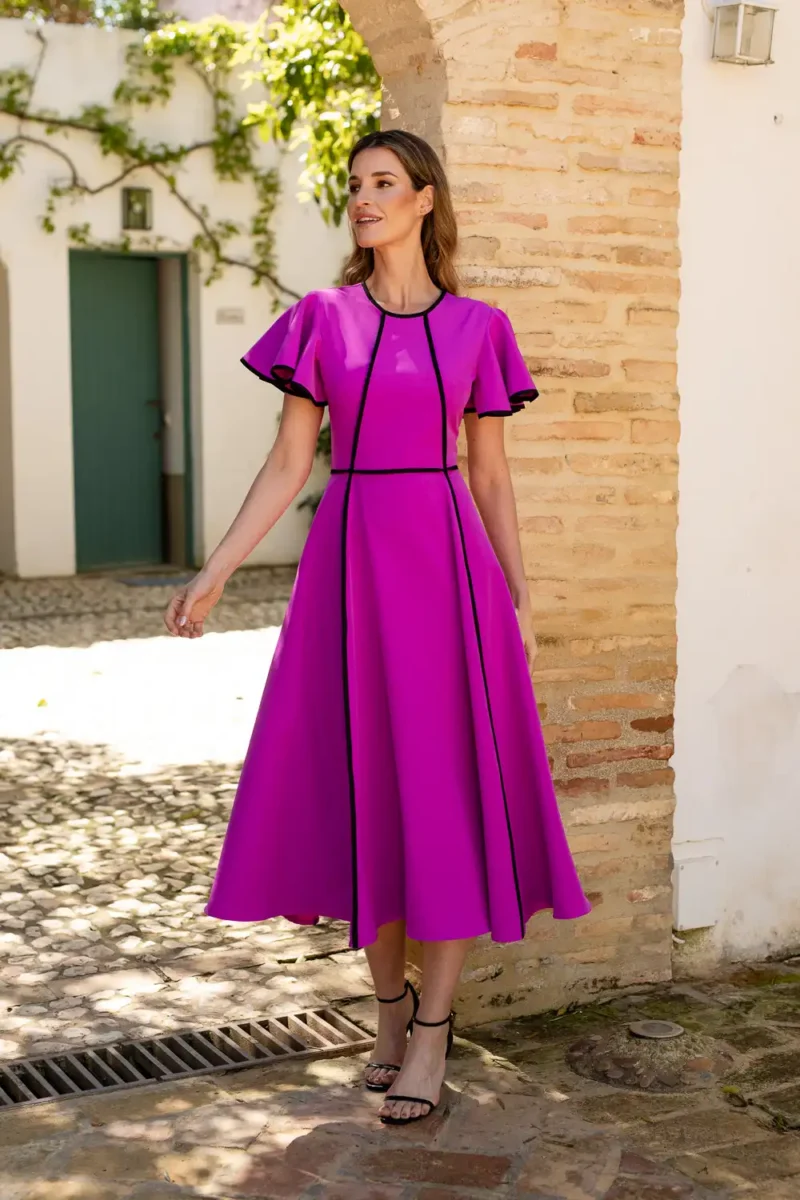 Vestido midi fucsia con vivos de decoración y volantes en las mangas.