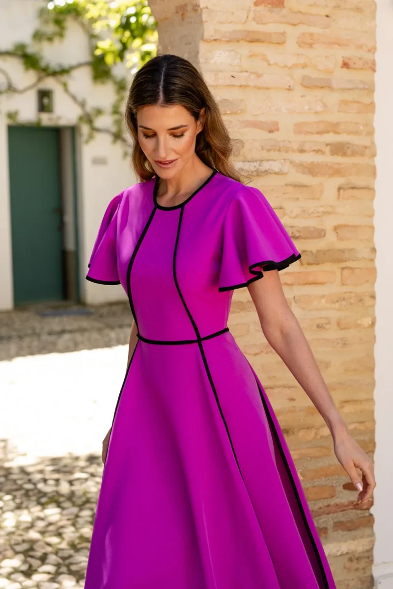 Vestido midi fucsia con vivos de decoración y volantes en las mangas.