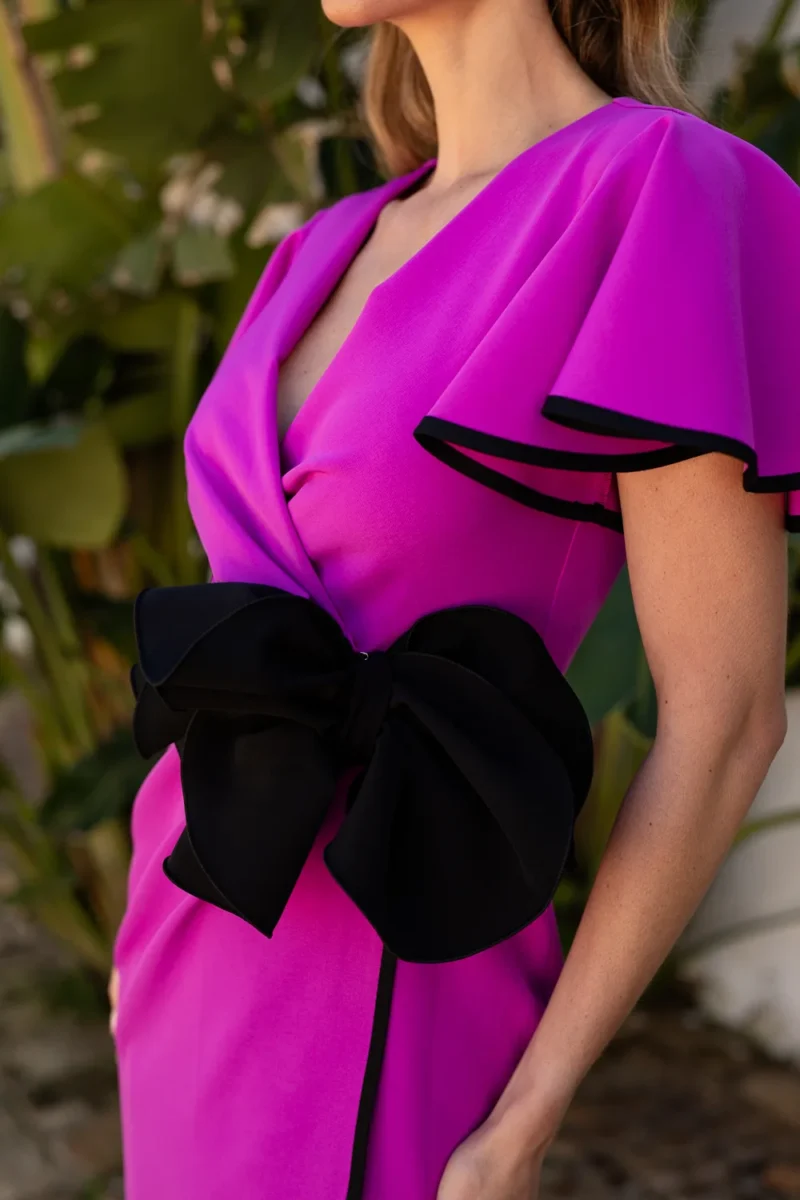 Vestido midi cruzado en color fucsia con flor de detalle.